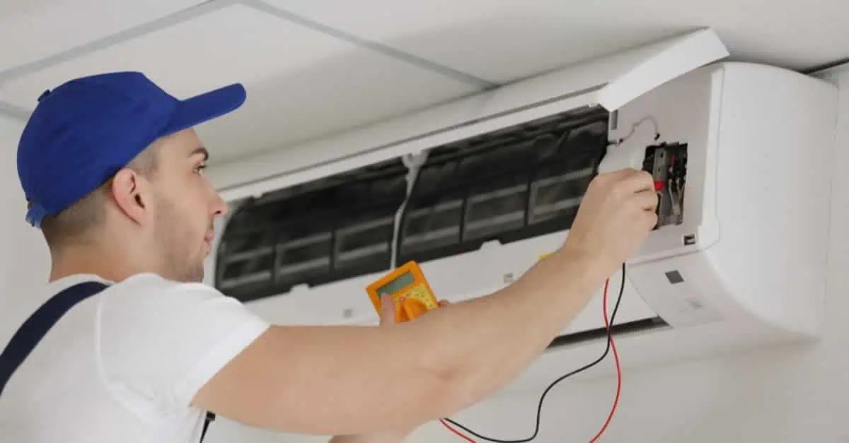 Electricien effectuant la maintenance d'une climatisation