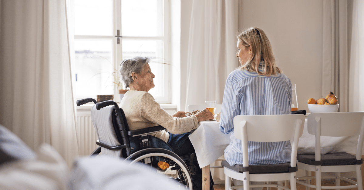 Assistante de vie avec une personne agée en fauteuil roulant