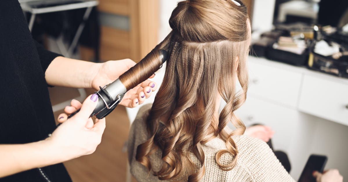 Coiffeuse réalise des boucles pour une cliente