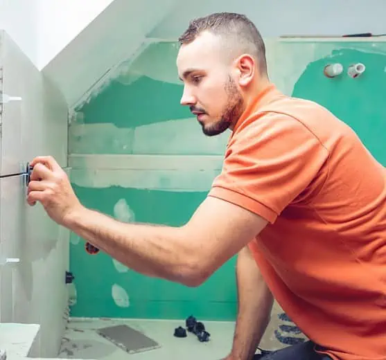 Carreleur effectuant la pose d'un carrelage dans une salle d'eau