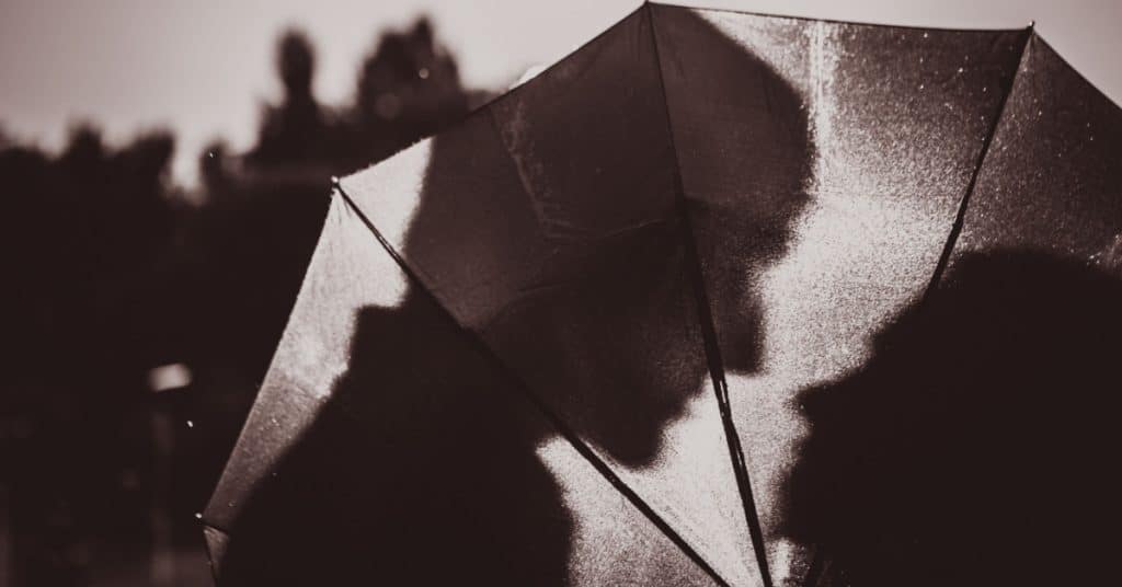 Silhouette d'un couple qui s'embrasse derrière un parapluie
