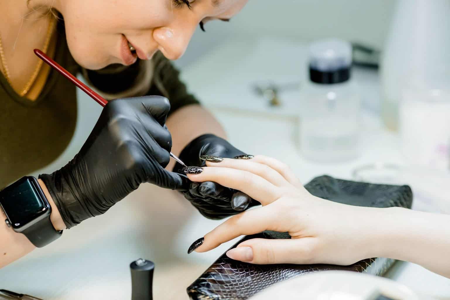 Manucure qui réalise une pose de vernis noir