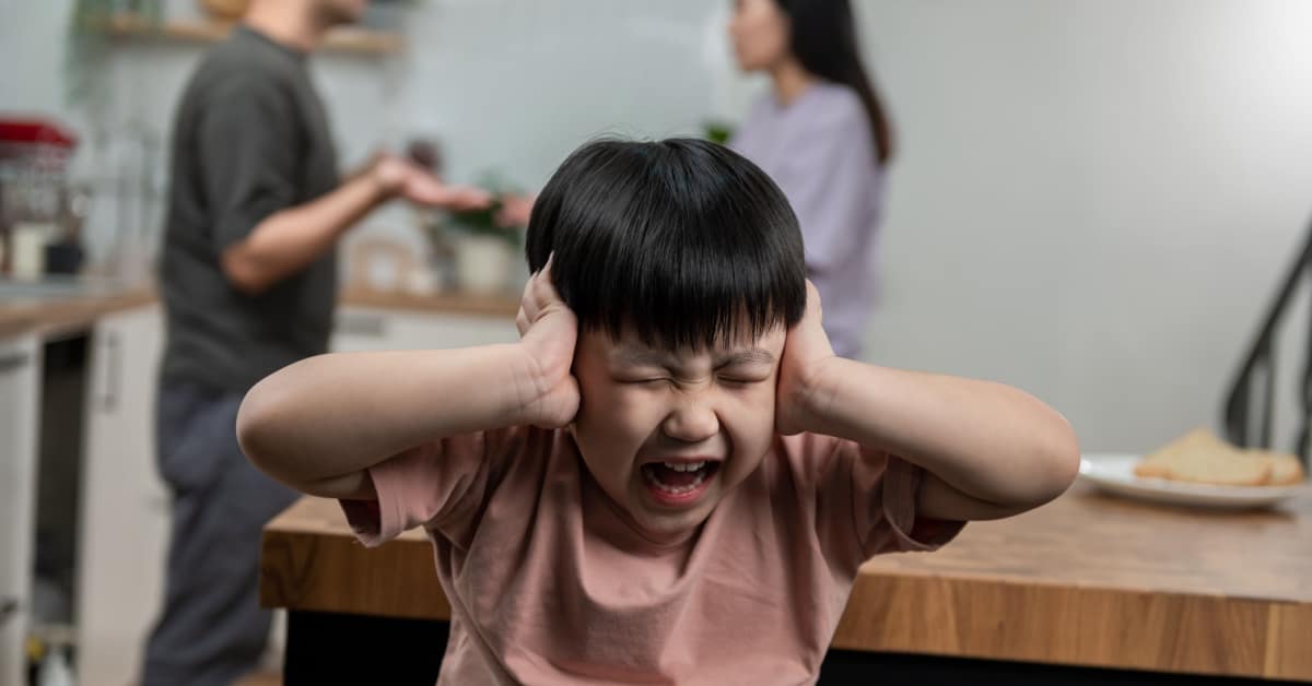 Enfant qui se bouche les oreilles lors d'une d'une dispute entre ses parents