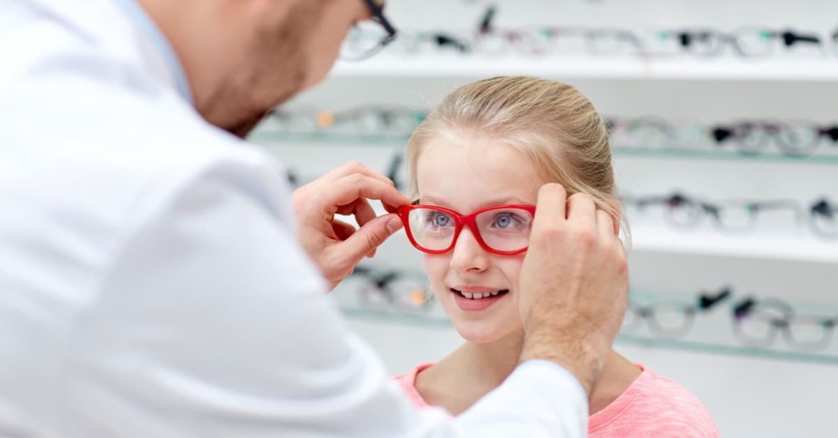 Opticien fait essayer des lunettes à une petite fille